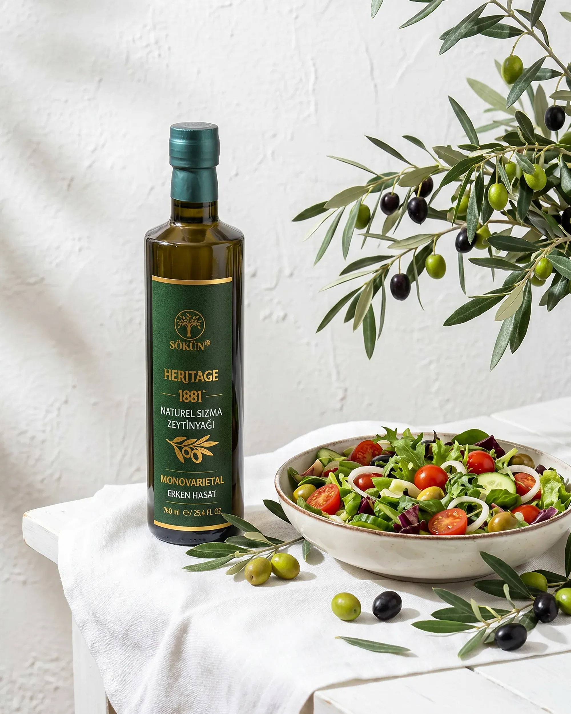 A bottle beside a bowl of salad on a white linen cloth