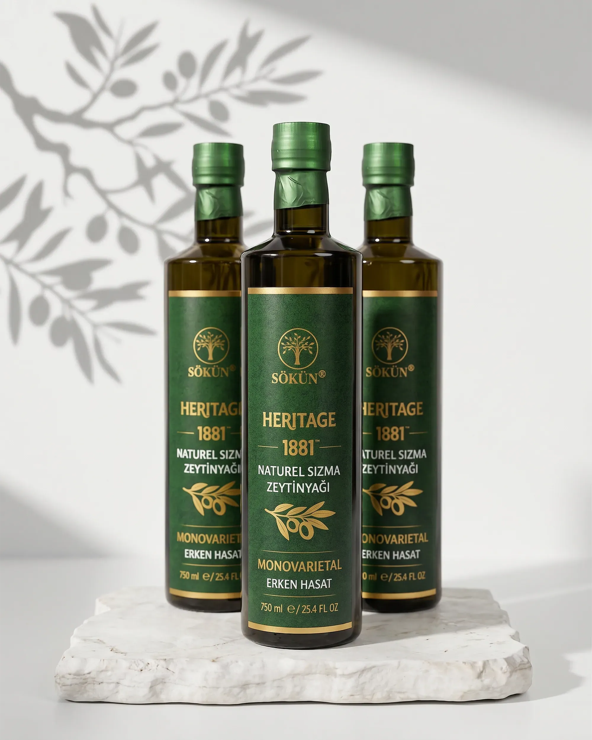 Three bottles on white stone with the shadow of an olive branch behind